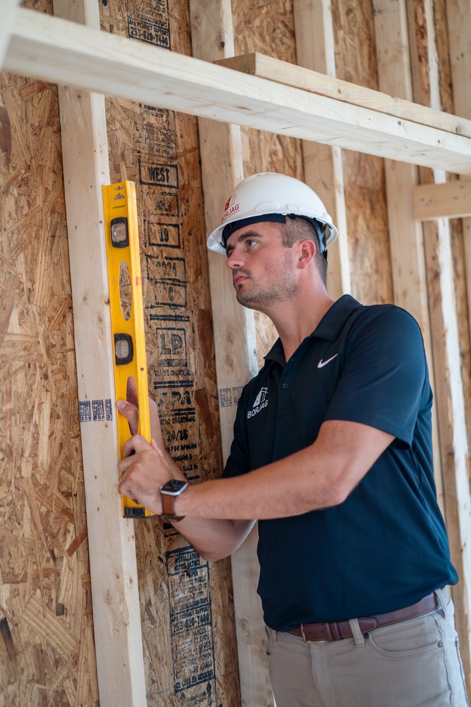 Checking a framed wall with a level during construction