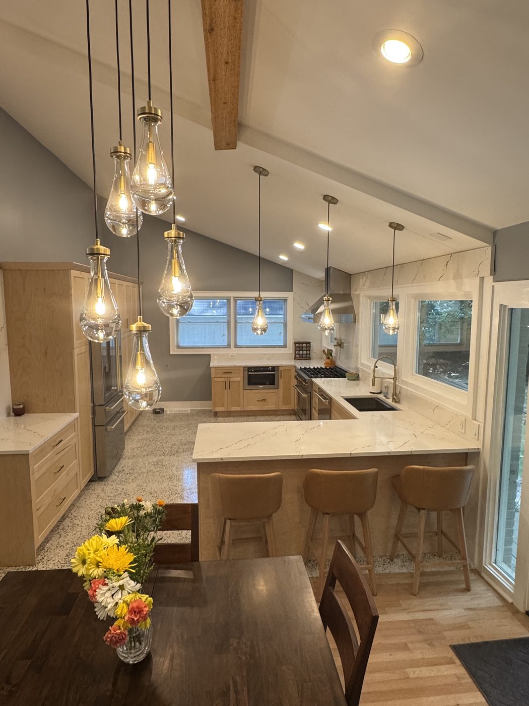 After: the same kitchen opened up — vaulted and light-filled, with the new engineered beam visible in the ceiling